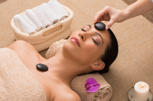 Beautiful Woman Receiving A Hot Stone Massage On Her Face In A Spa