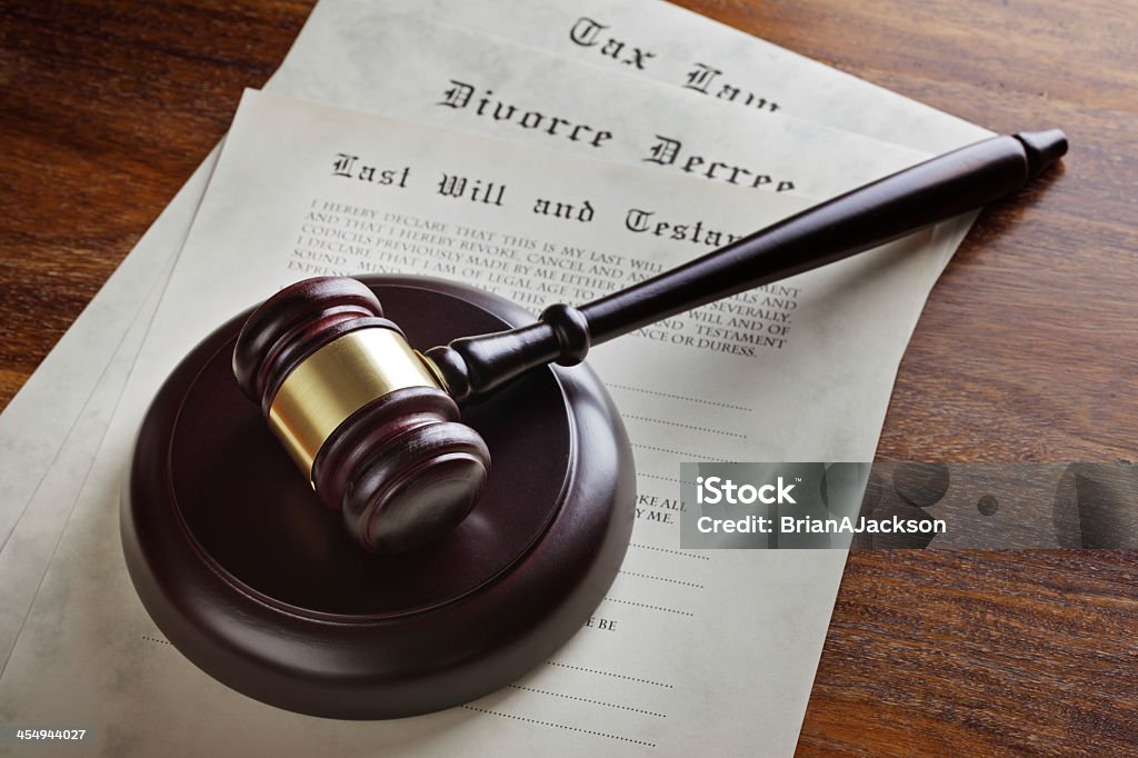 Judge's gavel atop a stack of court documents Gavel and legal papers last will and testament, divorce decree and tax law concept for the judicial system Divorce Stock Photo