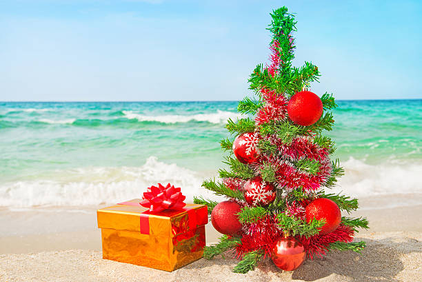 istock Christmas tree and many gift boxes on sea beach 454945147