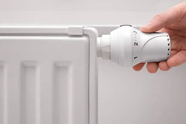 hand adjusting the temperature of heating radiator