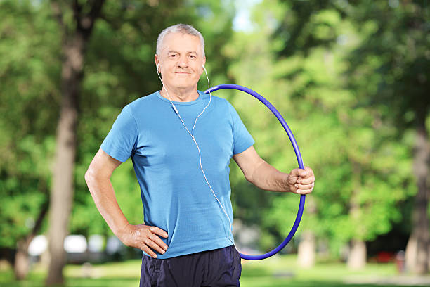 istock Mature athlete with headphones holding a hulahoop in park 454955893