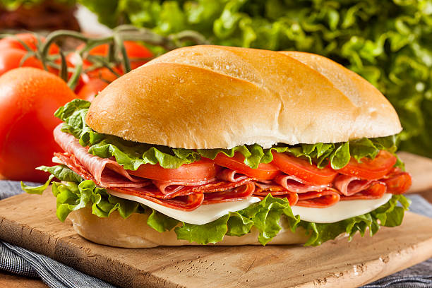 istock Large Italian sub sandwich on wooden cutting board 454956631