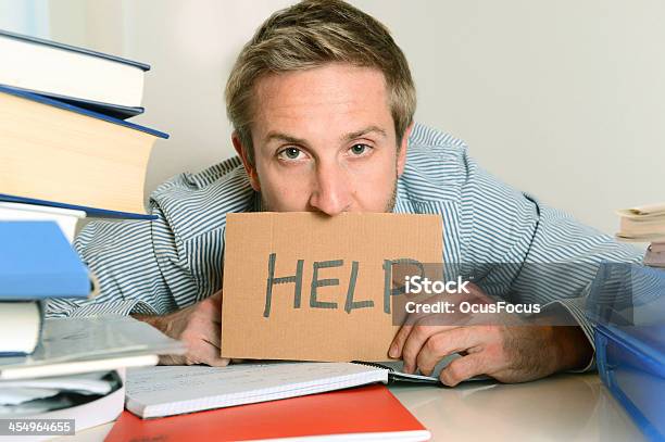 Young Man With Piles Of Book And A Cardboard Help Sign Stock Photo - Download Image Now