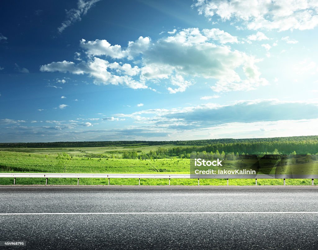 Green field next to an asphalt road asphalt road and perfect green field Road Stock Photo