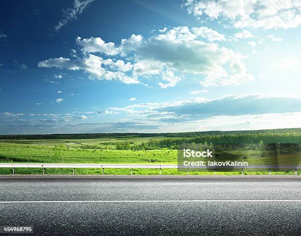 Green Field Next To An Asphalt Road Stock Photo - Download Image Now - Road, Side View, Landscape - Scenery