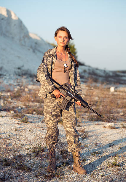 Young beautiful female soldier dressed in a camouflage with a gun in the location
