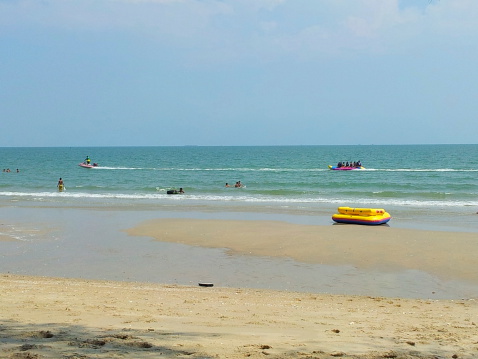 People have fun at Cha-am beach, Thailand on a sunny day.