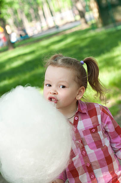istock girl eating cotton candy 454981185