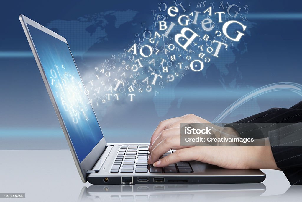 Hands working on a laptop representing online business Female hands typing on the laptop with flying letters Text Stock Photo