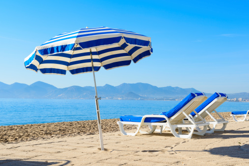 Parasol and sunbeds on a sandy beach in Cannes in the South of France.