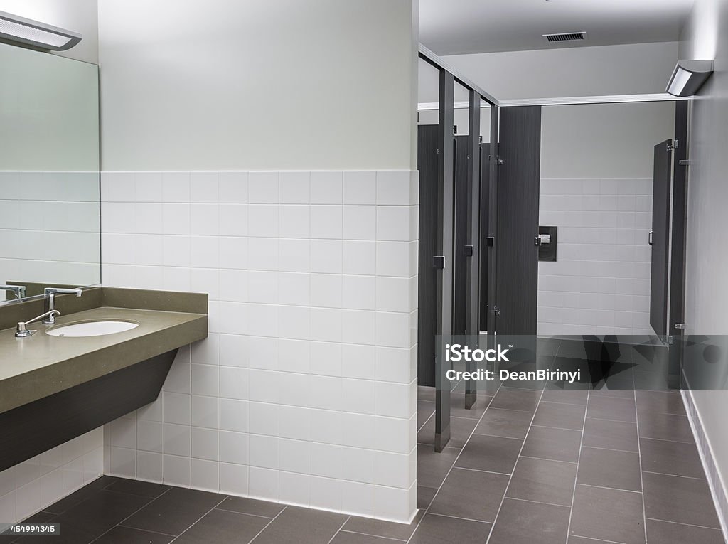 Commercial women's bathroom in neutral colors Commercial women's bathroom in neutral colors with sink and open stall doors. Business Stock Photo