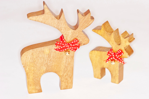 FESTIVEBRIEF2013  Wooden cut out reindeer toys or decorations with red bows for  scarves and a bell, against a white background using a macro lens and ringflash.