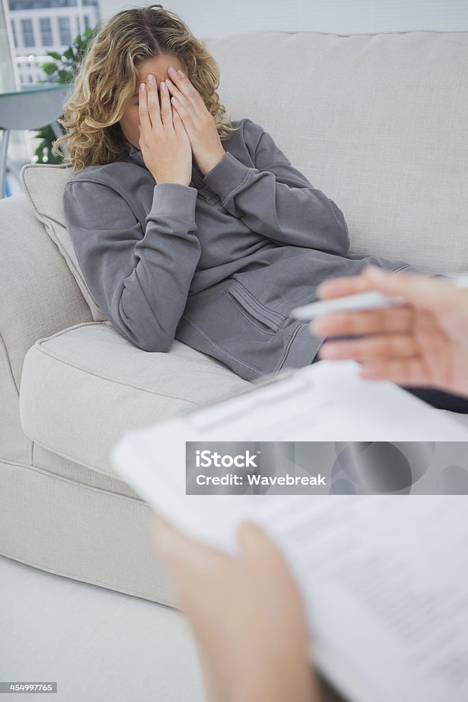 Upset patient crying on couch Upset patient crying on couch while the therapist is taking notes 30-39 Years Stock Photo