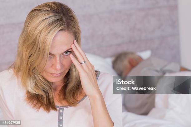 Frowning Woman With A Headache While Her Husband Is Sleeping 30-39세에 대한 스톡 사진 및 기타 이미지