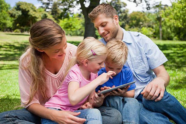 istock Smiling parents looking at their children playing with a tablet 454997977
