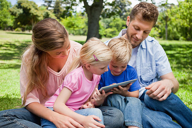 istock Cute children holding a tablet pc bein with thei parents 454998111