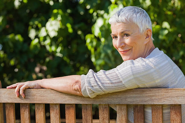 istock Cheerful elderly woman sitting alone on a bench 454998149