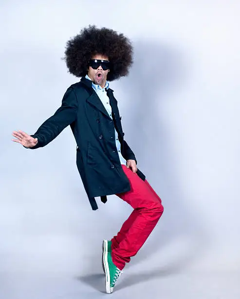 Rapper, breakdancer or hip hop dancer with a trendy afro hairstyle and sunglasses balancing on his tip toes as he performs his dance routine