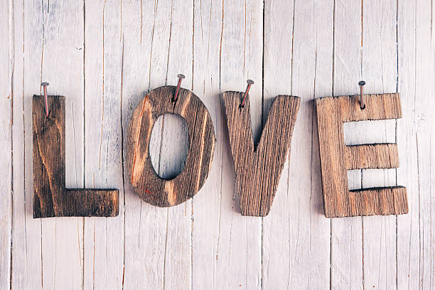 The word love in wooden letters nailed on a rustic wooden background.
