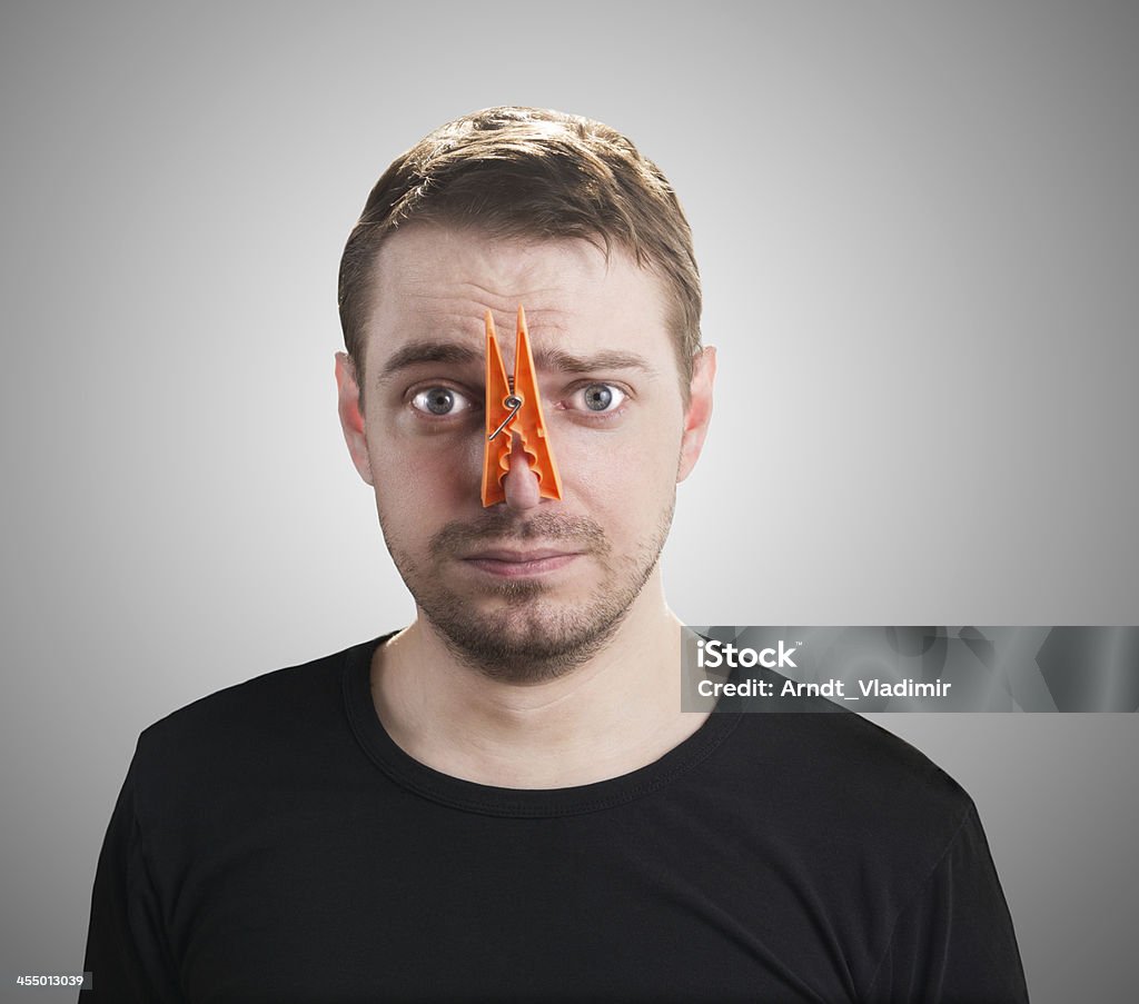 Man with clothespin on his nose. Portrait of caucasian man with orange clothespin on his nose - bad smell concept photography.  Clothespin Stock Photo