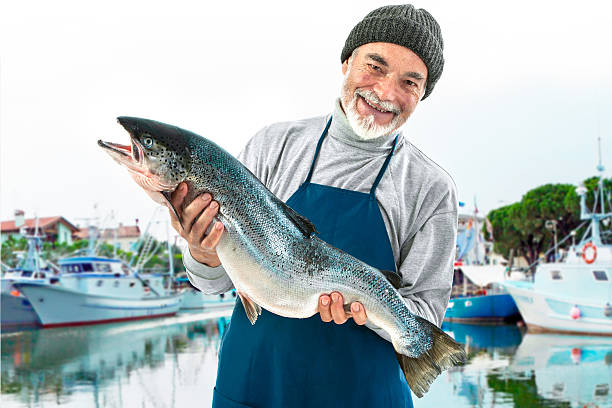 fisher con un grande pesce salmone dell'atlantico - fishermen harbor foto e immagini stock
