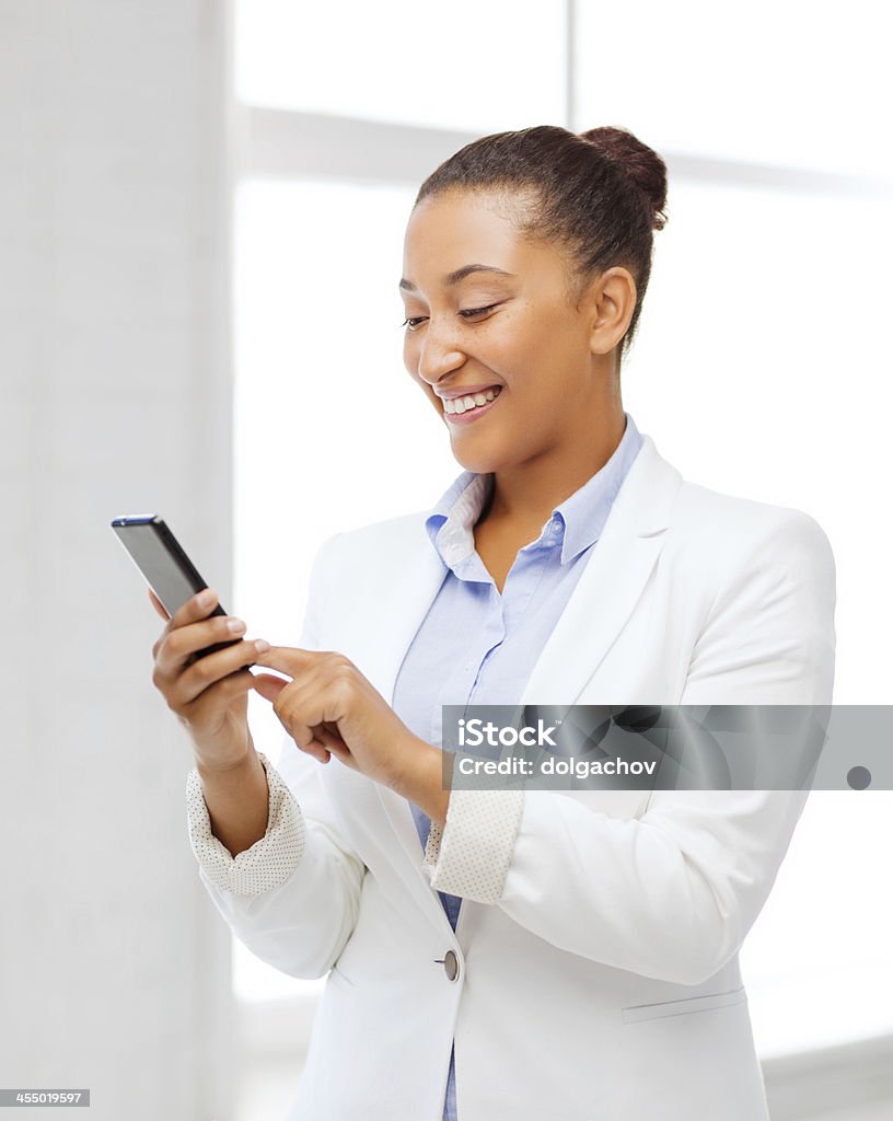 african businesswoman with smartphone in office business, and communication concept - smiling african businesswoman with smartphone in office Adult Stock Photo