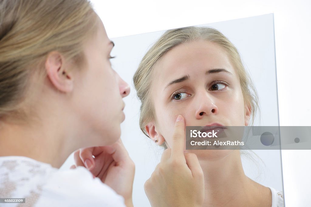 Teenage girl with the mirror Teenage girl checking her face for pimple in the mirror Mirror - Object Stock Photo