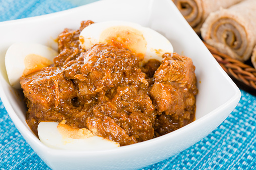 Ethiopian red chicken stew cooked with onions and berbere (chili and spices mix), topped with hard-boiled eggs. Served with injera.