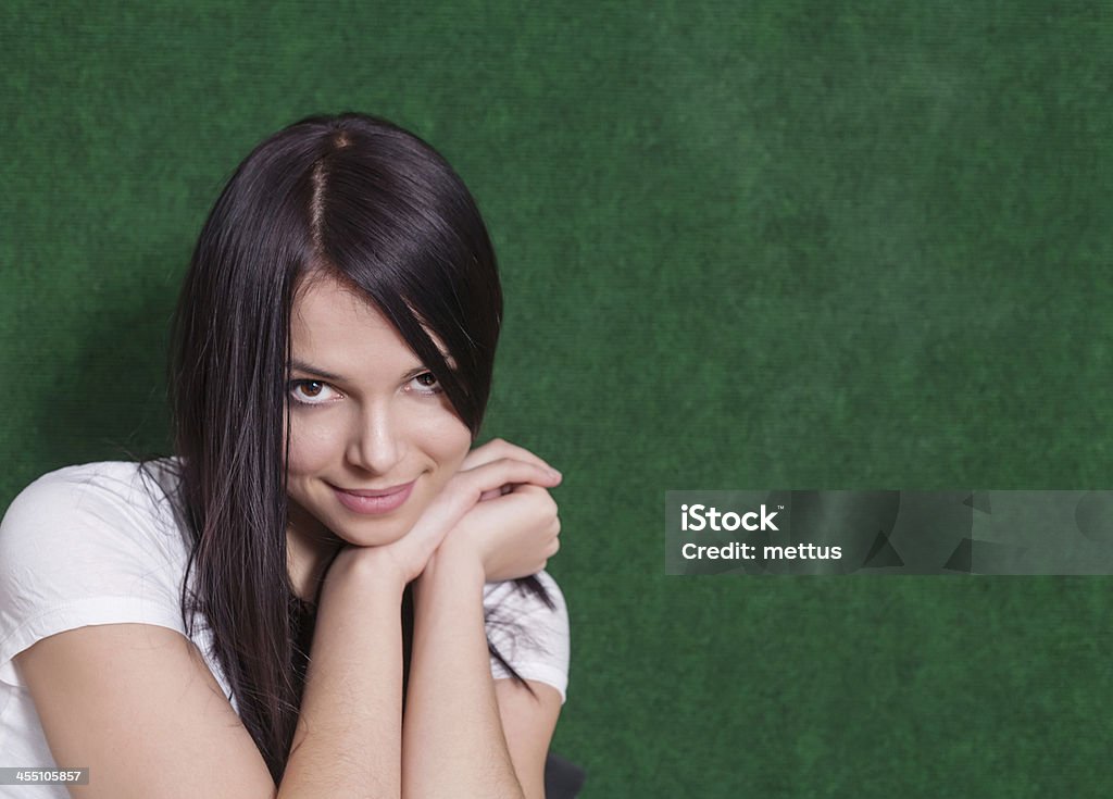 brunette green shoulders Shy women looking at camera. 20s brunette on green head and shoulders shot Adolescence Stock Photo