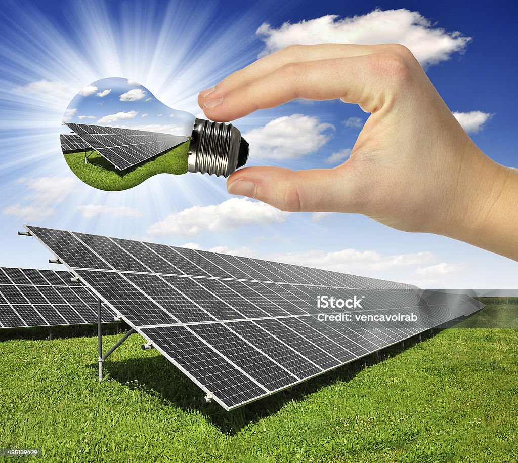 Solar panels Solar panels and hands holding bulb Blue Stock Photo