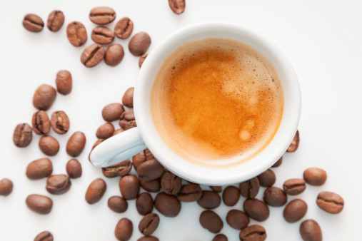 Cup of espresso and coffee beans on wooden table