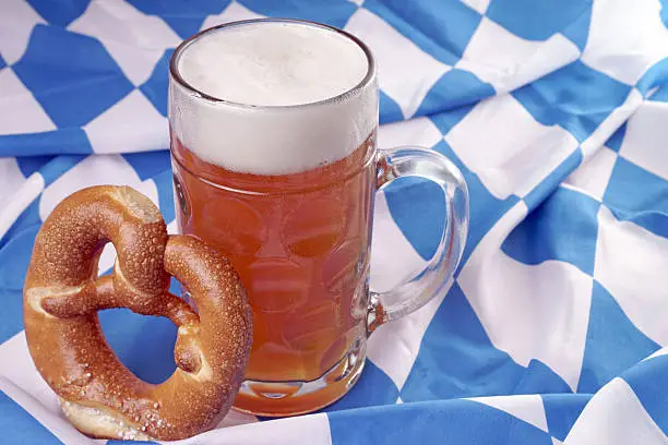 Beer mug with wheat beer and pretzel on a Bavarian flag