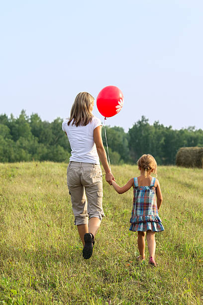 istock Mother and daughter going to mowed grass. View from back. 455230719