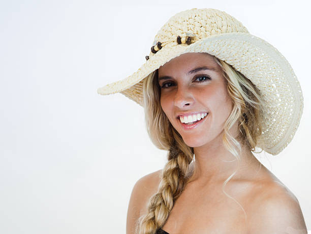 This happy teen model is smiling and wearing a straw summer hat
