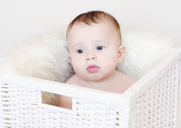 istock Sad baby sits in white basket 455235323