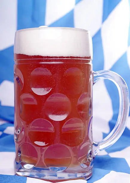 Beer mug with white beer on a Bavarian flag