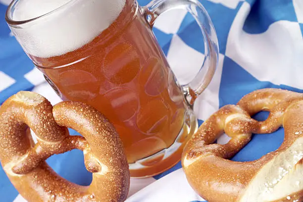 Beer mug with wheat beer and pretzel on a Bavarian flag