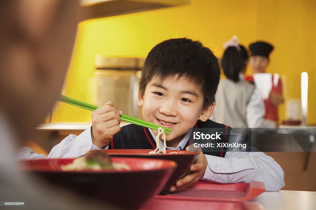 Boy eats noodles in school cafeteria School boy eats noodles in school cafeteria 10-11 Years Stock Photo