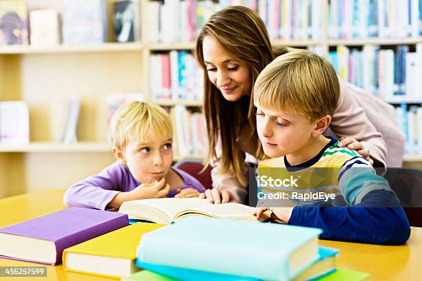 Helpful Librarian Or Teacher Aiding Children In Library Stock Photo - Download Image Now