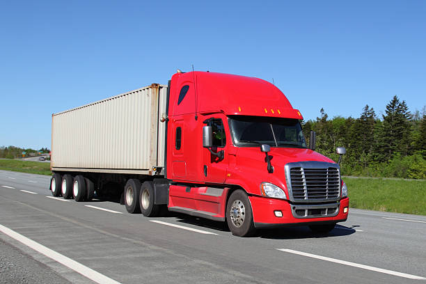 istock Red semi-truck on cloudless highway hauling white trailer 455264359