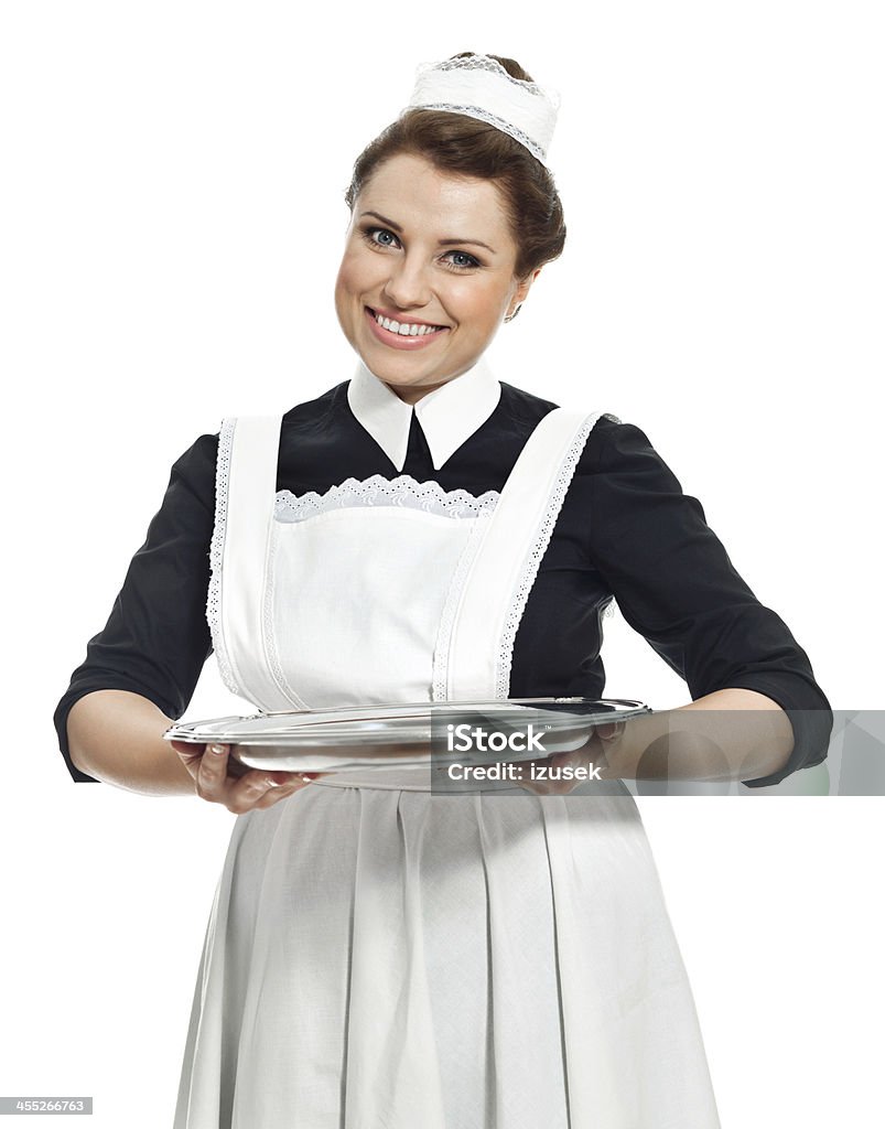 Victorian Style Maid Portrait of cheerful vintage maid holding an empty tray in hands and smiling at camera. Studio shot, white background. Victorian Style Stock Photo