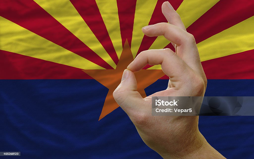 ok gesture in front of arizona us state flag man showing excellence or ok gesture in front of complete wavy american state flag of arizona symbolizing best quality, positivity and succes Achievement Stock Photo