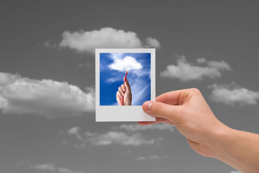 Holding instant cloud photo on a black sky background.