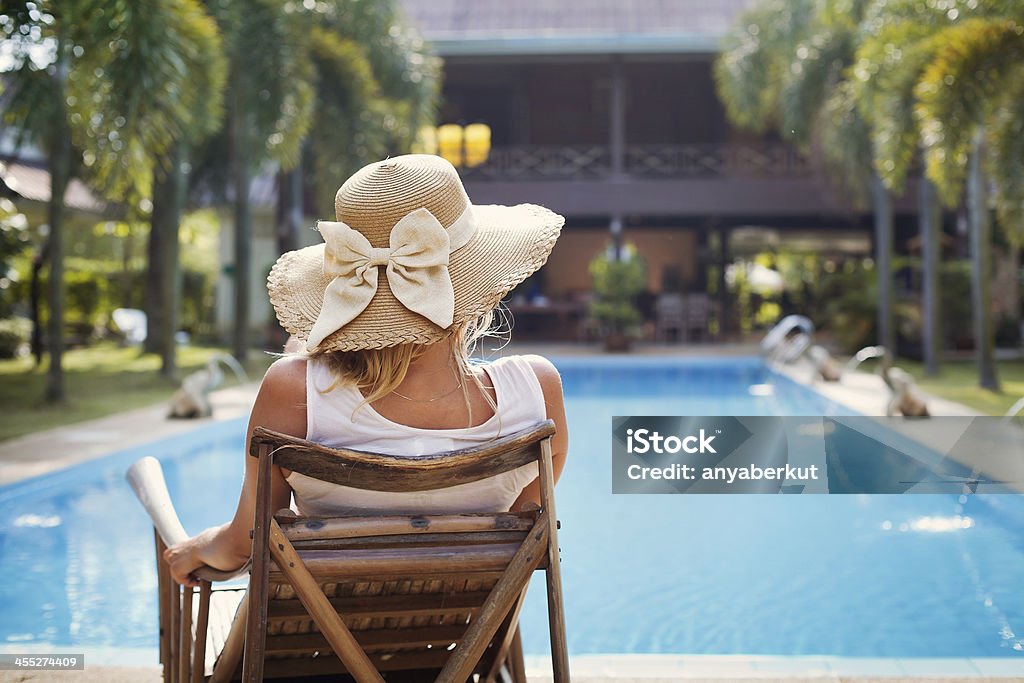 A woman sunbathing by the pool sunbath near swimming pool, fashion woman in hat Beach Stock Photo