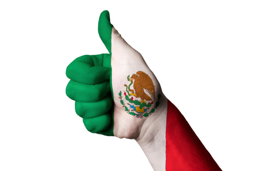 Hand with thumb up gesture in colored mexico national flag as symbol of excellence, achievement, good, - for tourism and touristic advertising, positive political, cultural, social management of country