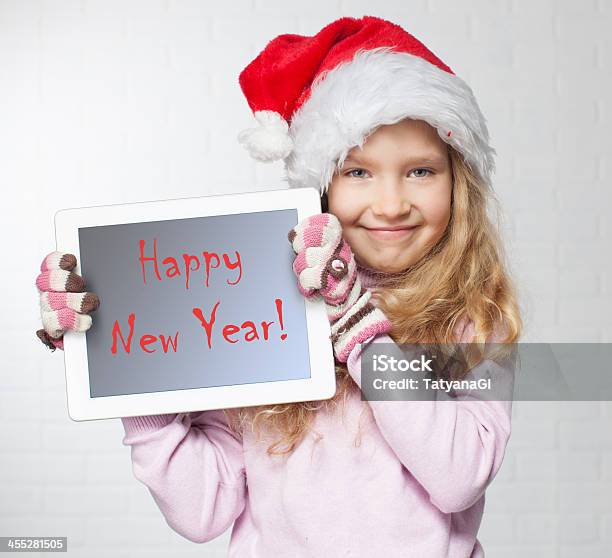 Girl In Santa Hat Holding Tablet Reading Happy New Year Stock Photo - Download Image Now