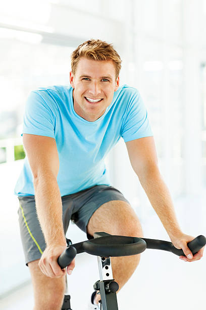 istock Man Smiling While Exercising On Bike In Gym 455294661