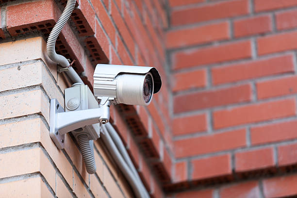 istock Video surveillance camera in courtyard on brick wall 455302623
