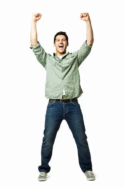 Handsome young man cheers with arms raised into the air. Vertical shot. Isolated on white.