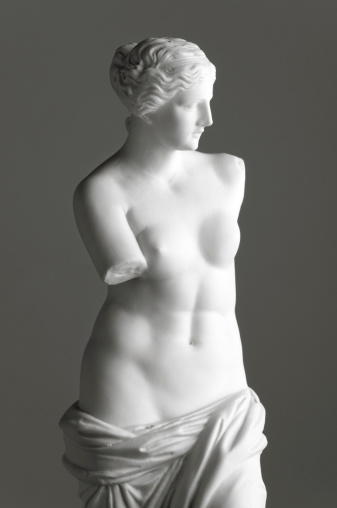 Vintage copy statue of Venus (Aphrodite) de Milo, a famous Greek sculpture dating back to about 100 BC, discovered in 1820 on the Aegean island of Milos. The original statue is in the Louvre museum in Paris. Vintage-styled fine art image on a grey background with added light grain.